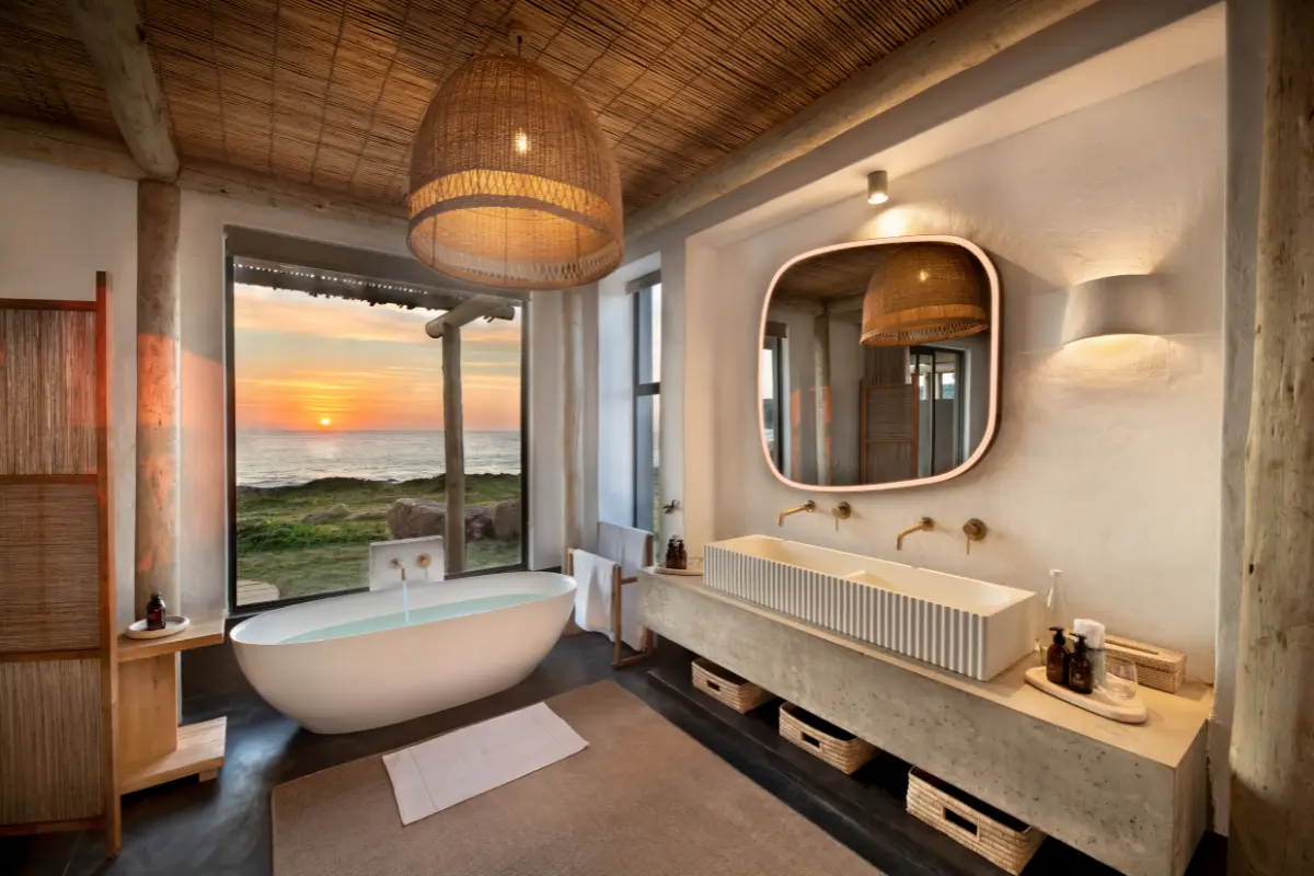 Suite bathroom with freestanding bath overlooking the ocean at sunset