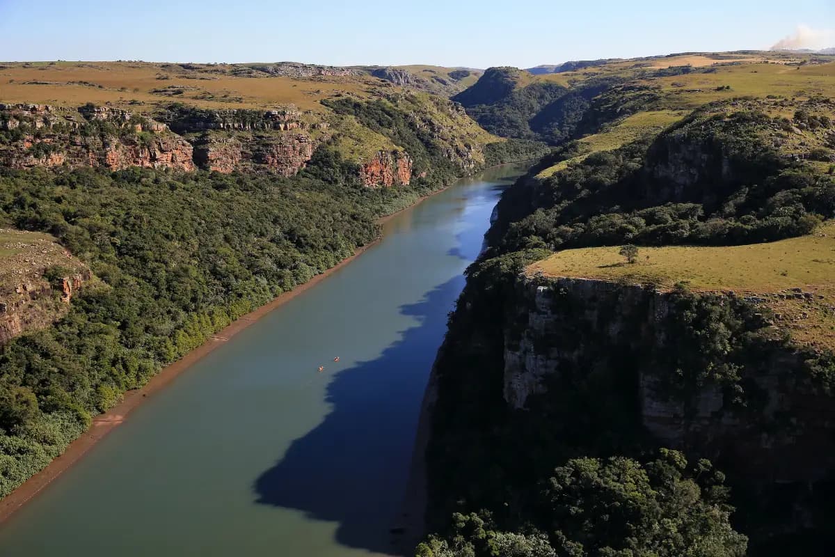 A river winding between steep green slopes toward the sea at Mtentu on the Wild Coast, South Africa