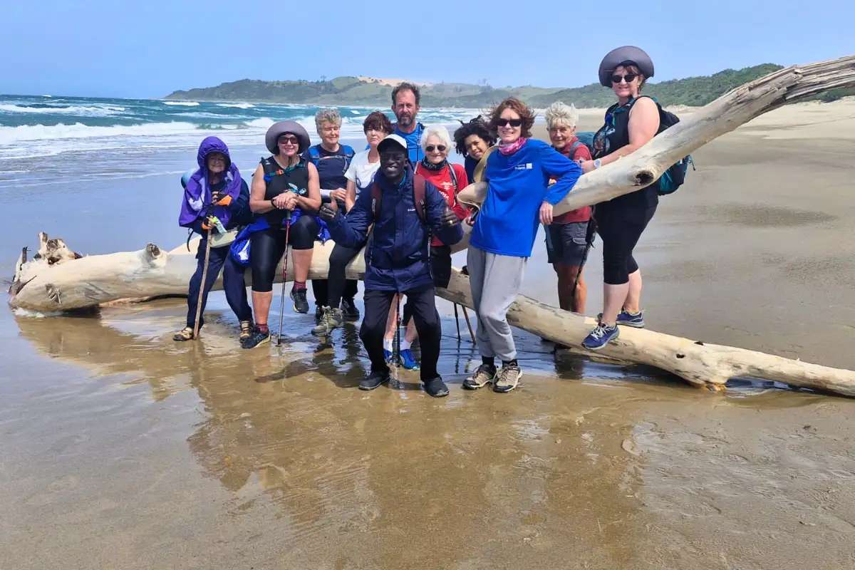 Group gathered around driftwood on the beach