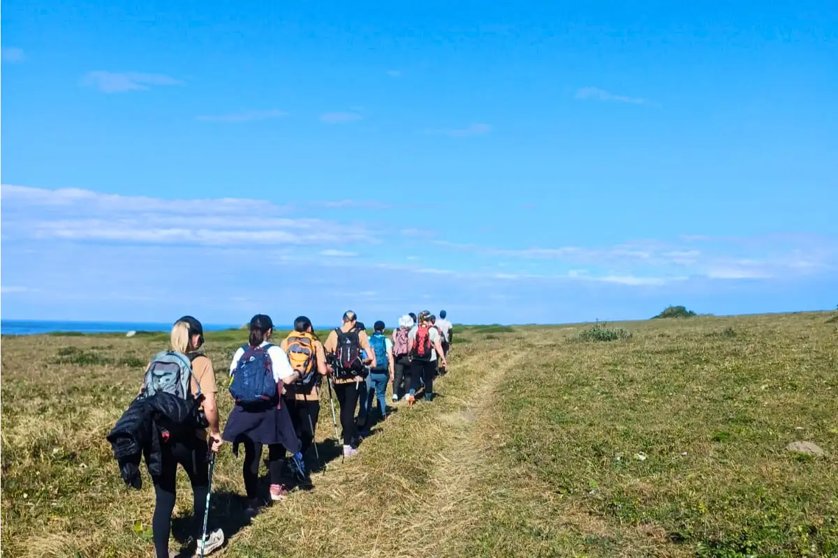 Hikers on an open trail heading towards the ocean