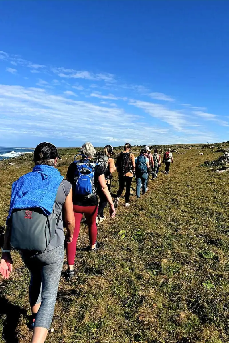 Long line of hikers in single file along a Wild Coast clifftop trail with the Indian Ocean stretching behind them